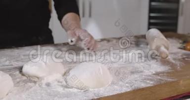 女厨师在厨房的桌子上把面粉扔到比萨饼面团上。